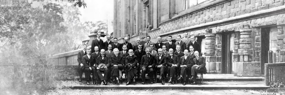 Black-and-white group photo of early quantum physicists outside a stone building