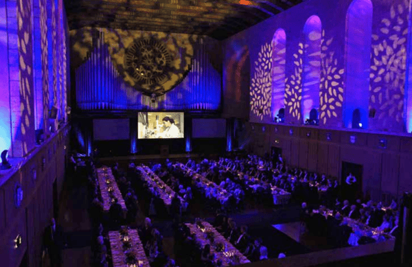 A formal dinner in Winthrop Hall under purple lighting